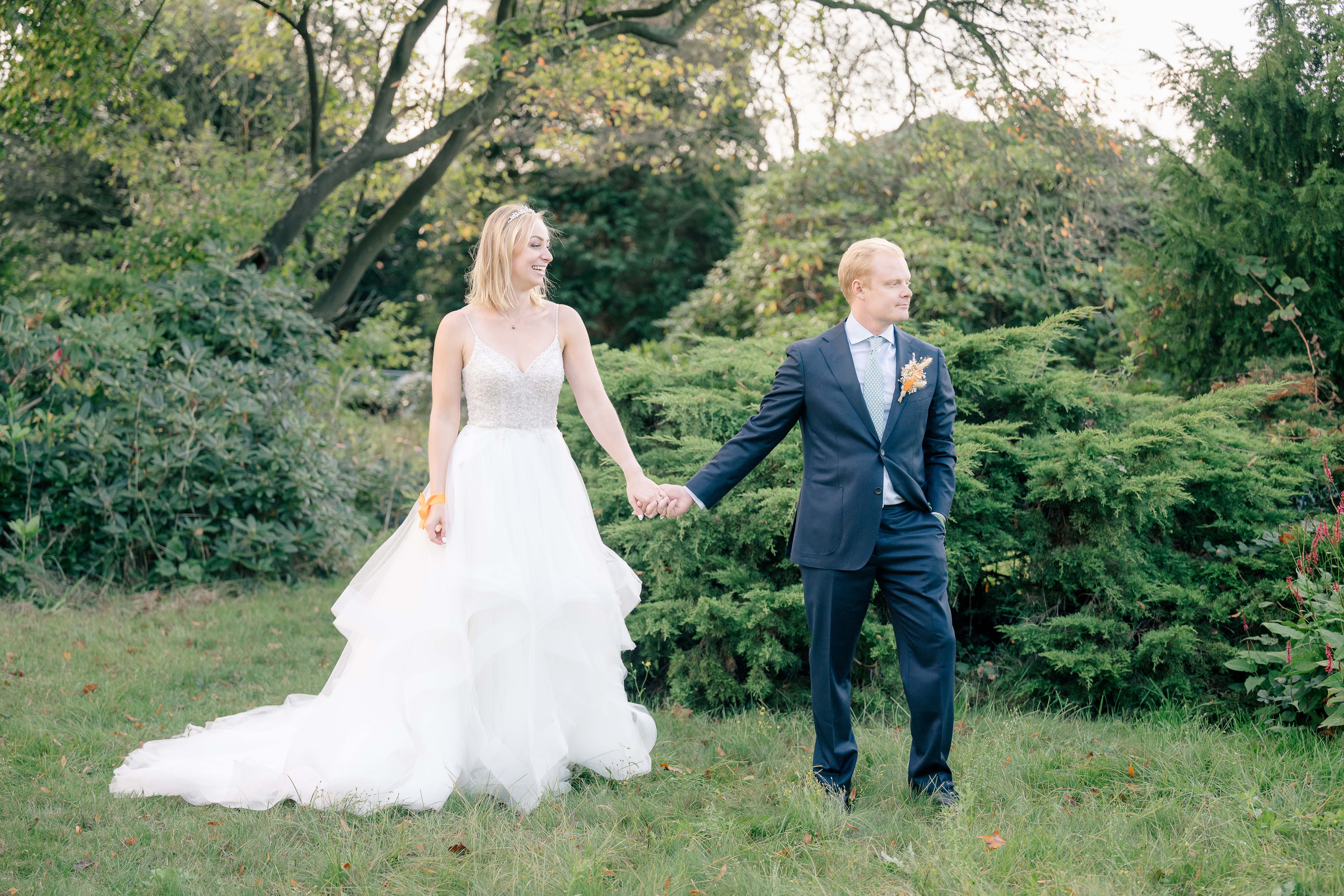 Bride and groom portrait holding hands and looking into the distance at a garden wedding